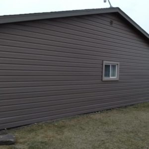 Exterior view of building with singular window and brown seamless steel siding.