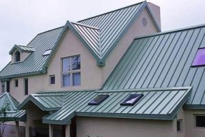 Exterior view of commercial building with tan paint and green steel roofing.