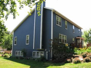 Multi-story home with blue steel siding and white trim.