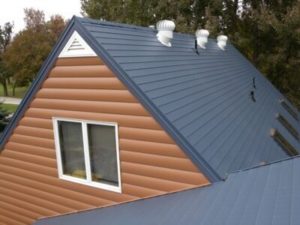 Dark gray metal roof on a house with with faux log cabin siding