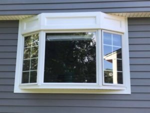 Bay window with a white frame in a wall with gray siding